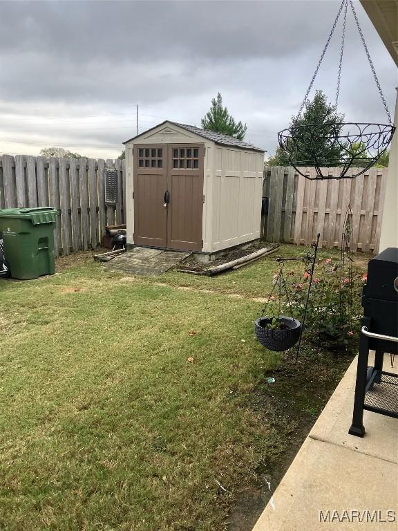 view of yard featuring a storage shed, a fenced backyard, and an outdoor structure