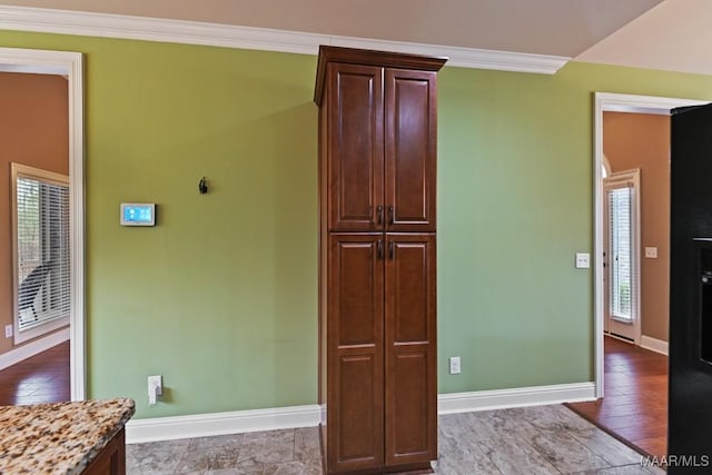 kitchen with ornamental molding, light stone countertops, and hardwood / wood-style floors