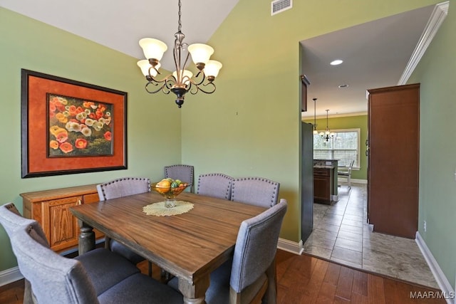 dining room with lofted ceiling, a notable chandelier, crown molding, and dark wood-type flooring