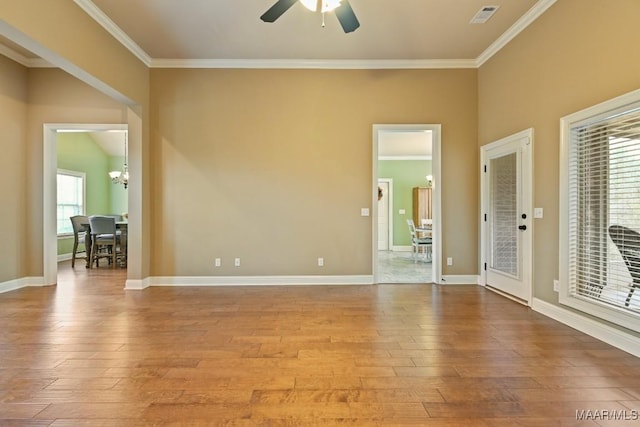 spare room with ornamental molding, ceiling fan with notable chandelier, and light hardwood / wood-style flooring