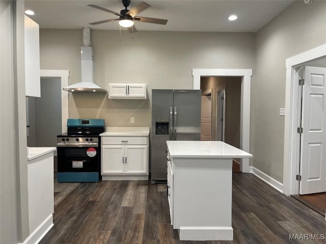 kitchen with wall chimney exhaust hood, white cabinetry, dark hardwood / wood-style flooring, ceiling fan, and stainless steel appliances