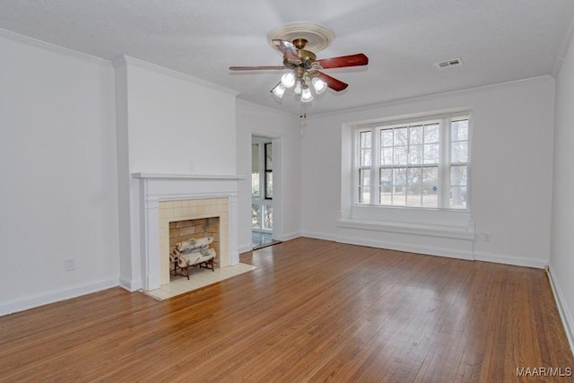 unfurnished living room with a tile fireplace, crown molding, ceiling fan, and light hardwood / wood-style floors