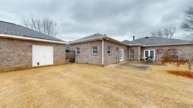 back of property with a patio area, a shingled roof, a yard, and brick siding