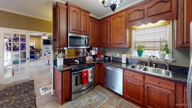 kitchen featuring dark stone countertops, crown molding, appliances with stainless steel finishes, and a sink