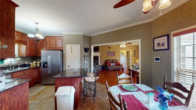 kitchen with ceiling fan with notable chandelier, a sink, a kitchen island, hanging light fixtures, and stainless steel refrigerator with ice dispenser