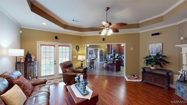 living area featuring a tray ceiling, french doors, crown molding, visible vents, and dark wood-type flooring