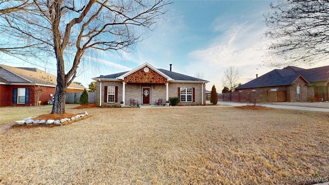 view of front of home featuring a front yard, brick siding, and fence