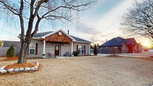 view of front facade with brick siding, fence, and a front lawn