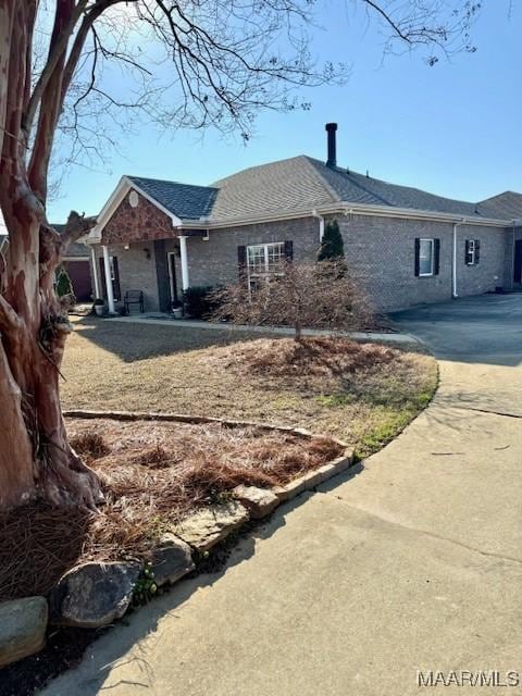 single story home with a shingled roof, brick siding, and driveway