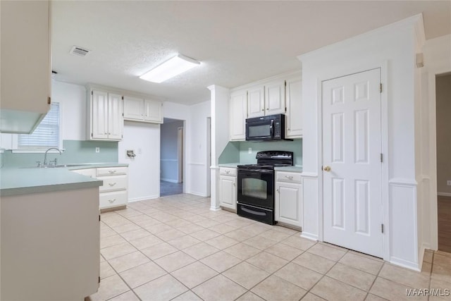 kitchen featuring light countertops, white cabinets, visible vents, and black appliances