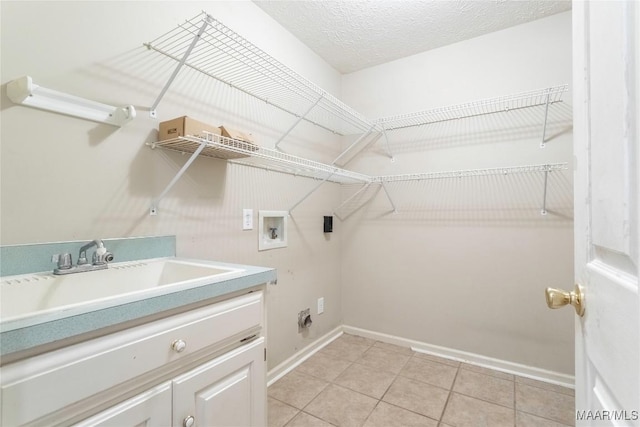 clothes washing area featuring light tile patterned floors, hookup for an electric dryer, a textured ceiling, washer hookup, and a sink