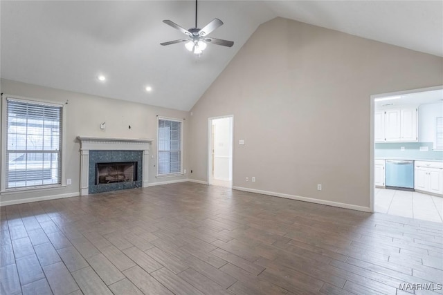 unfurnished living room with high vaulted ceiling, a tile fireplace, light wood-style flooring, and a ceiling fan