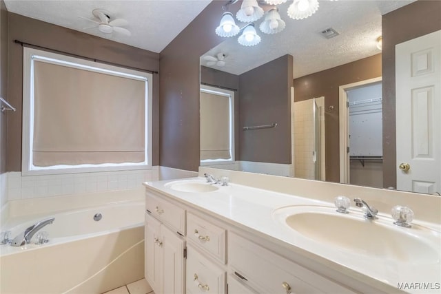 full bathroom featuring a garden tub, a textured ceiling, visible vents, and a sink