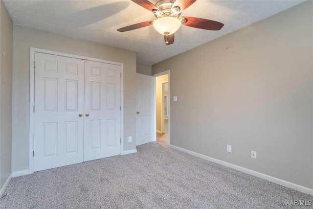 unfurnished bedroom with carpet, a closet, baseboards, and a textured ceiling