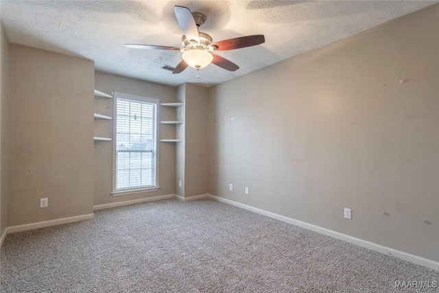 carpeted spare room with a ceiling fan, visible vents, a textured ceiling, and baseboards