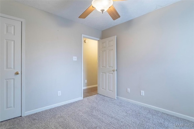 carpeted spare room featuring ceiling fan, baseboards, and a textured ceiling