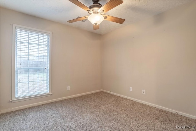 carpeted empty room with a ceiling fan, baseboards, and a textured ceiling