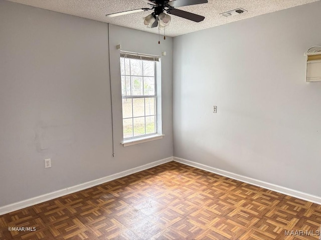 spare room with ceiling fan, dark parquet floors, and a textured ceiling