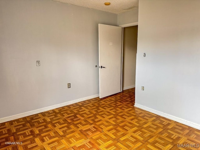 unfurnished room with parquet floors and a textured ceiling