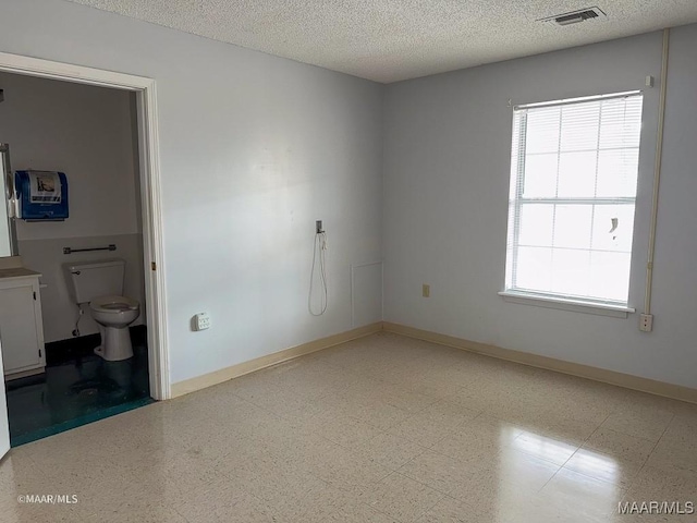 interior space featuring connected bathroom and a textured ceiling