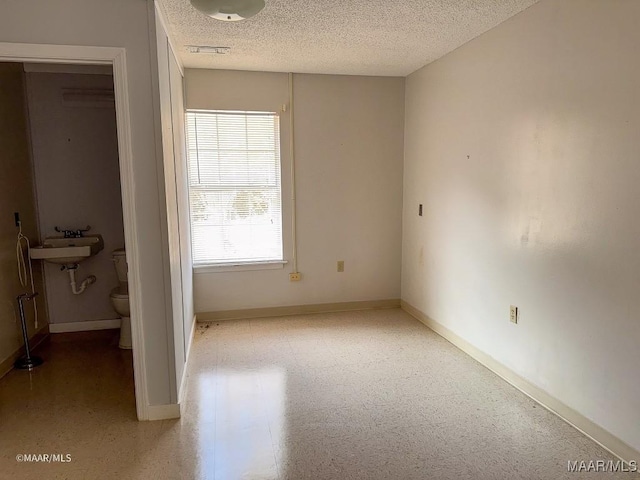 unfurnished bedroom featuring sink and a textured ceiling