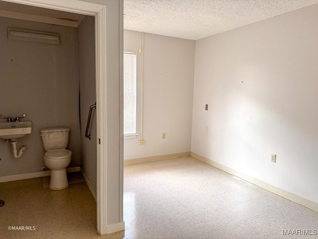 bathroom with a healthy amount of sunlight, toilet, and a textured ceiling