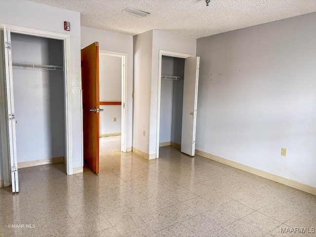 unfurnished bedroom featuring multiple closets and a textured ceiling