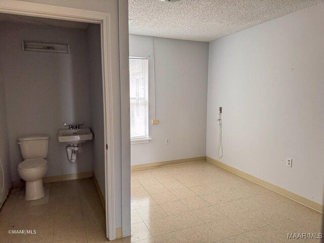 bathroom with toilet, sink, and a textured ceiling