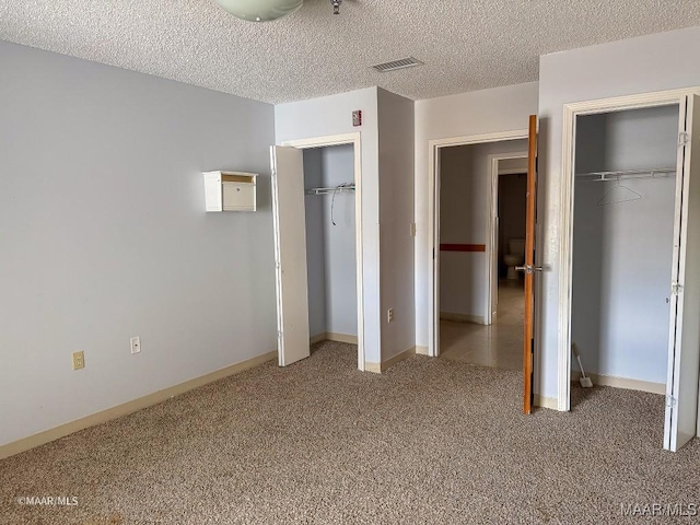 unfurnished bedroom with multiple closets, carpet floors, and a textured ceiling