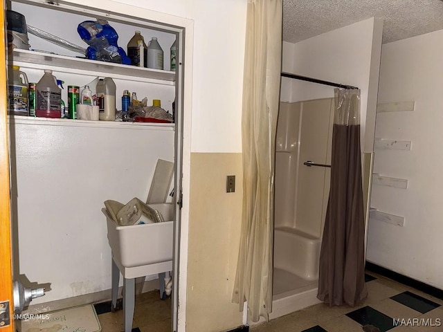 bathroom with curtained shower and a textured ceiling