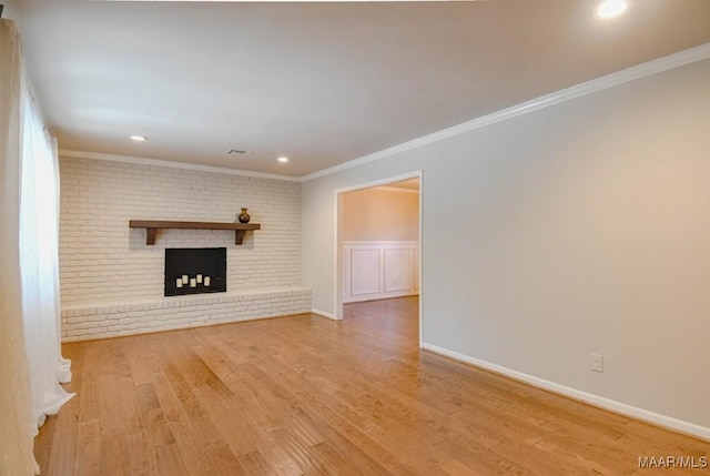 unfurnished living room featuring wood finished floors, baseboards, recessed lighting, crown molding, and a brick fireplace