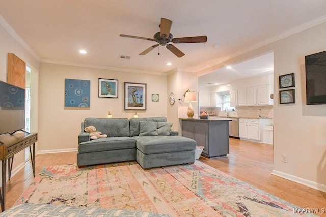 living room featuring baseboards, ceiling fan, crown molding, and light wood finished floors