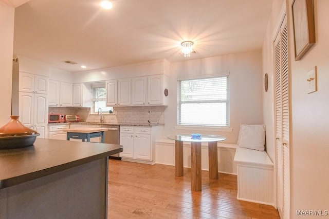 kitchen with backsplash, white cabinetry, light wood-style floors, white microwave, and dishwasher