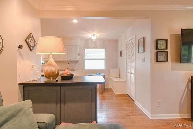 kitchen featuring dark countertops, white cabinetry, crown molding, light wood finished floors, and baseboards