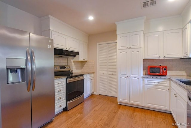 kitchen with light wood finished floors, visible vents, light stone countertops, under cabinet range hood, and stainless steel appliances