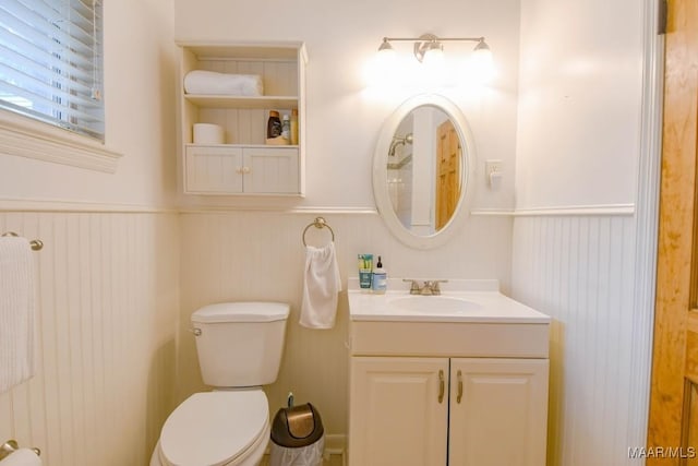 bathroom with vanity, toilet, and wainscoting