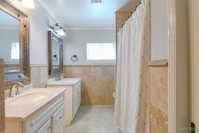 bathroom with a wainscoted wall, tile walls, crown molding, and a sink