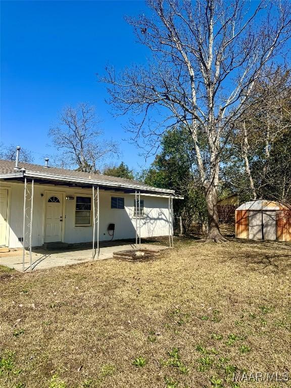 rear view of property with a yard, a patio area, and a storage shed