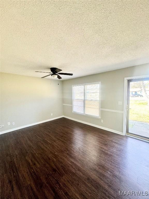 unfurnished room with ceiling fan, a healthy amount of sunlight, a textured ceiling, and dark hardwood / wood-style flooring