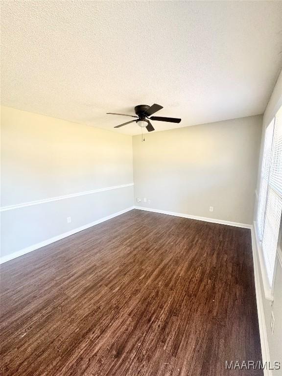 empty room with ceiling fan, dark hardwood / wood-style floors, and a textured ceiling