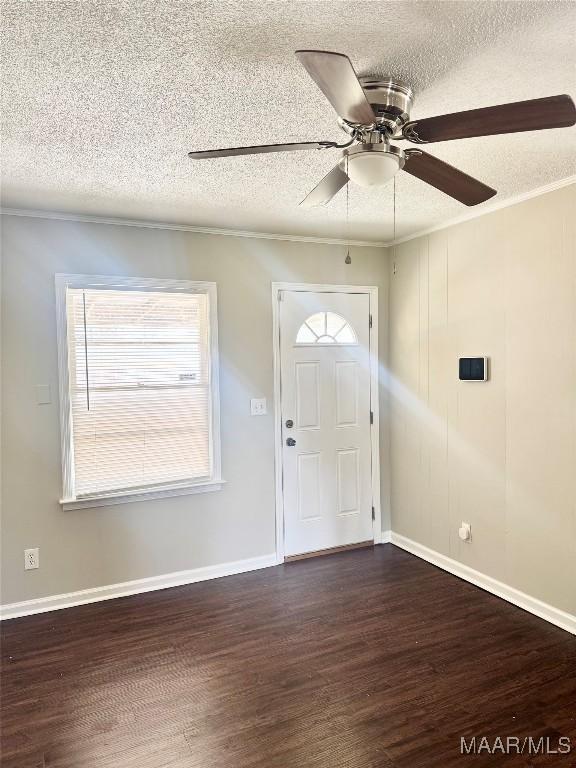 entryway featuring dark hardwood / wood-style flooring, ceiling fan, ornamental molding, and a textured ceiling