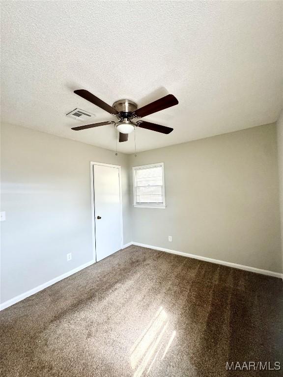 spare room featuring ceiling fan, carpet floors, and a textured ceiling