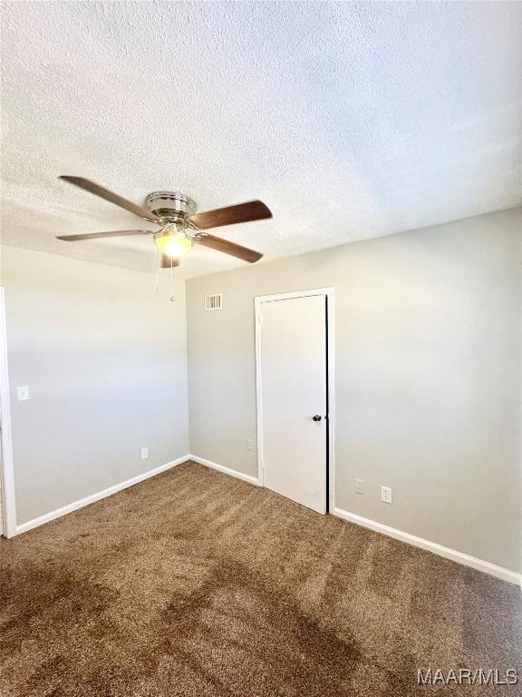 carpeted spare room with ceiling fan and a textured ceiling