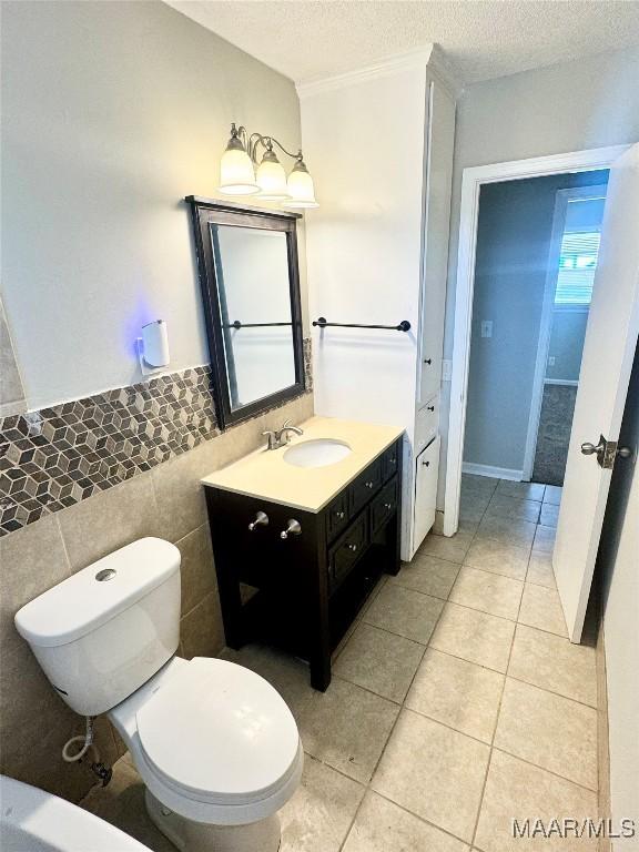 bathroom featuring tile patterned floors, toilet, a textured ceiling, tile walls, and vanity