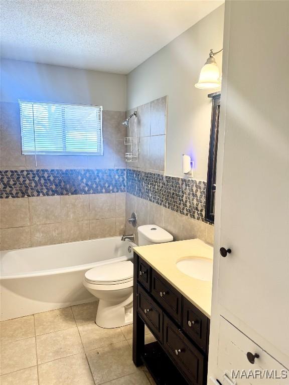 full bathroom with toilet, tiled shower / bath, a textured ceiling, tile walls, and vanity