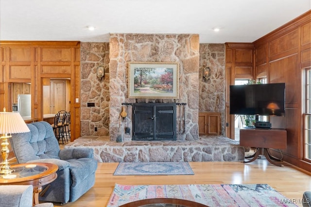 living room with a stone fireplace and light wood-type flooring