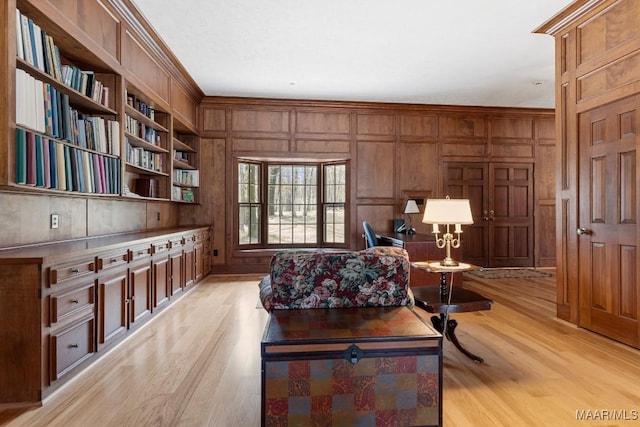 office featuring built in shelves, light hardwood / wood-style flooring, ornamental molding, and wood walls