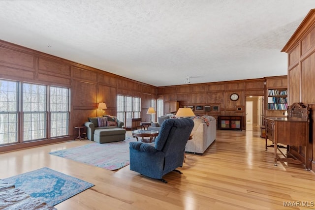 living room with ornamental molding, wooden walls, light hardwood / wood-style floors, and a textured ceiling