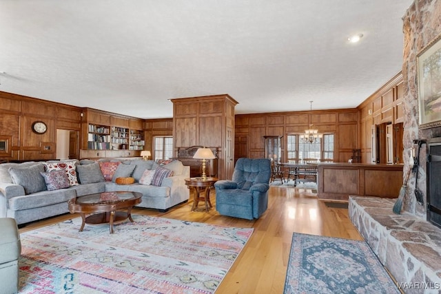 living room with wood walls, a chandelier, ornamental molding, light hardwood / wood-style floors, and a textured ceiling