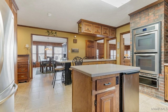 kitchen featuring light tile patterned floors, fridge, ornamental molding, double oven, and a kitchen island